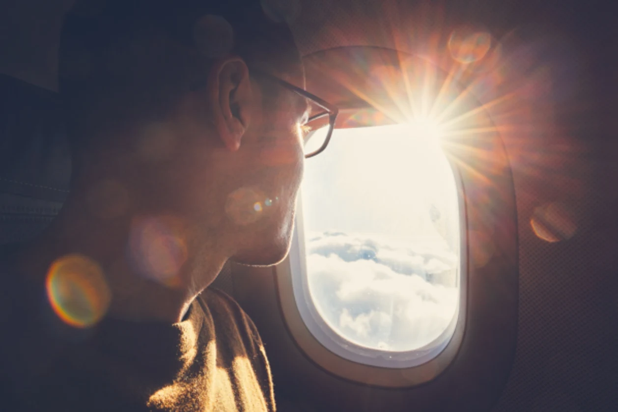 man traveling by airplane looking out window
